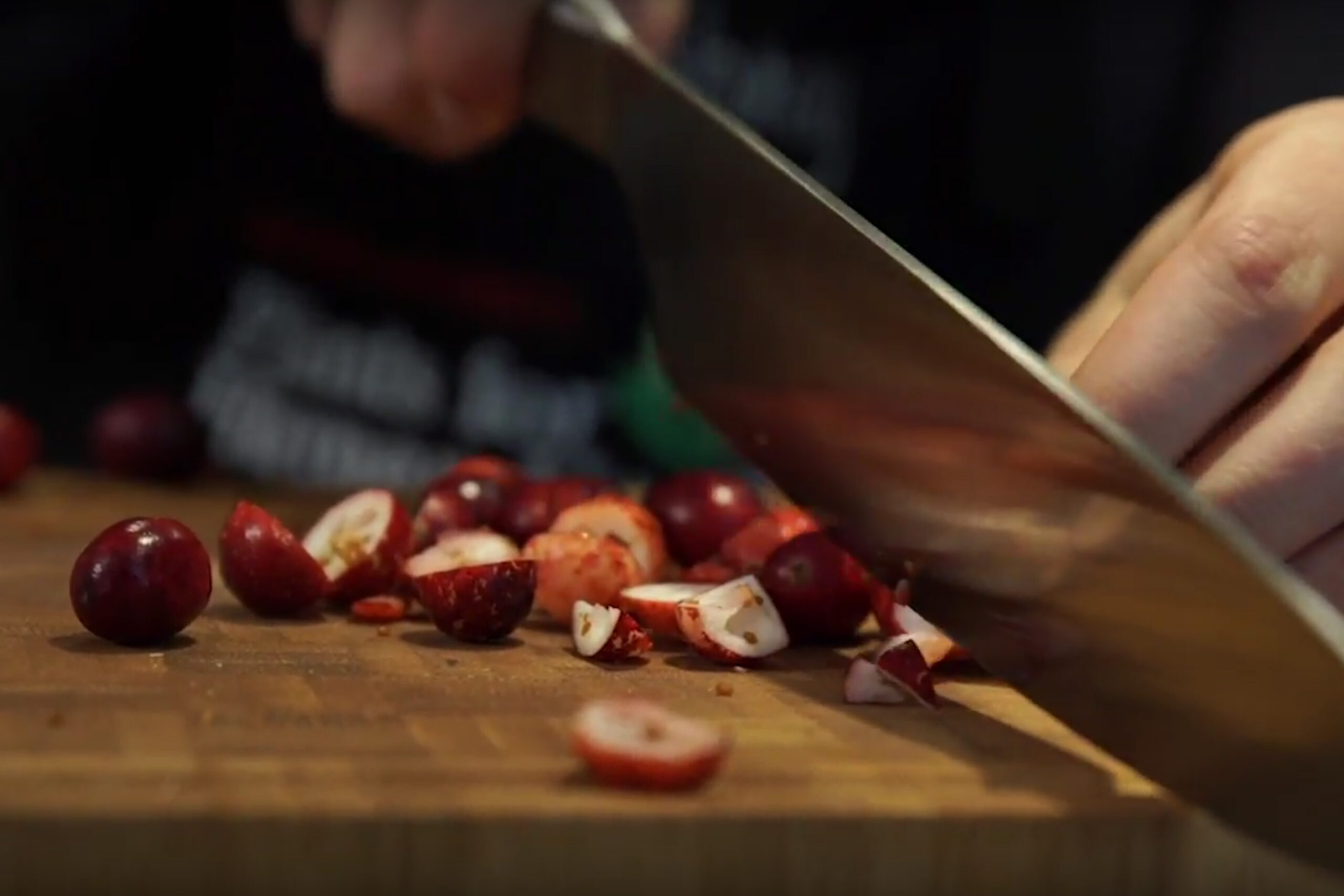 Knife cutting cranberries on a wooden cutting board