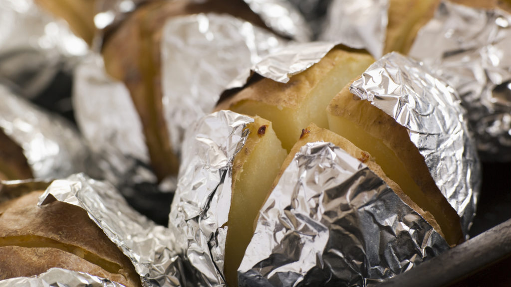 Close-up Photo of Baked Potatoes Wrapped in Foil On a Baking Tray