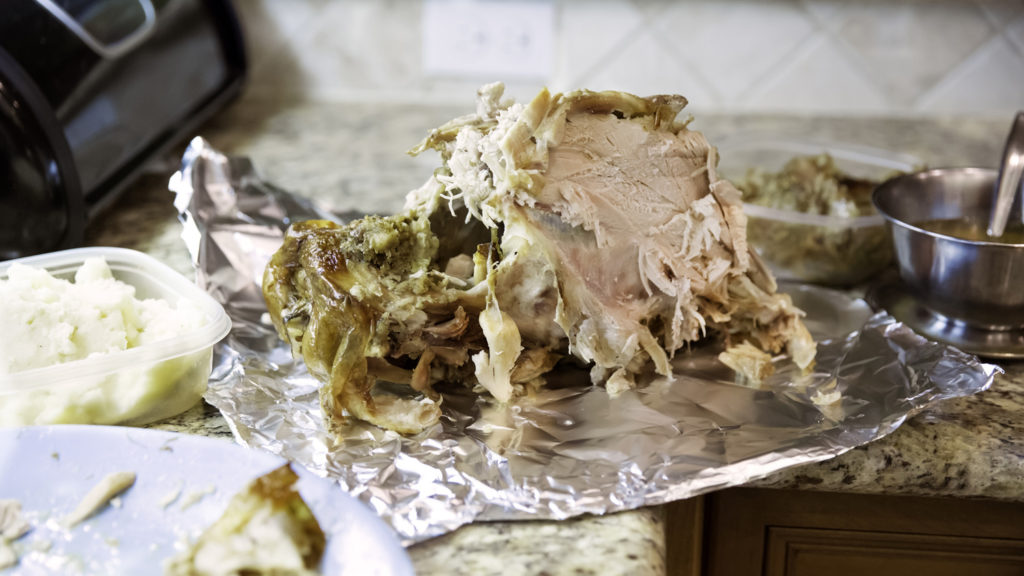 Leftover sliced turkey on a sheet of aluminum foil on the kitchen counter after a big holiday dinner.