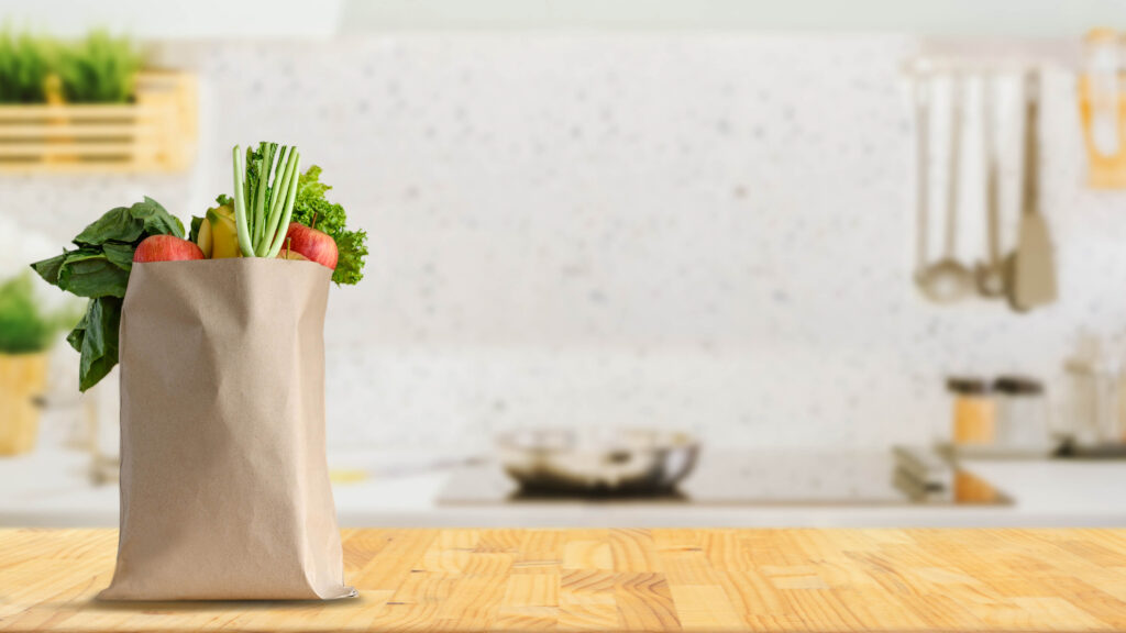 Paper shopping bag full of fruit and vegetable groceries on a kitchen counter