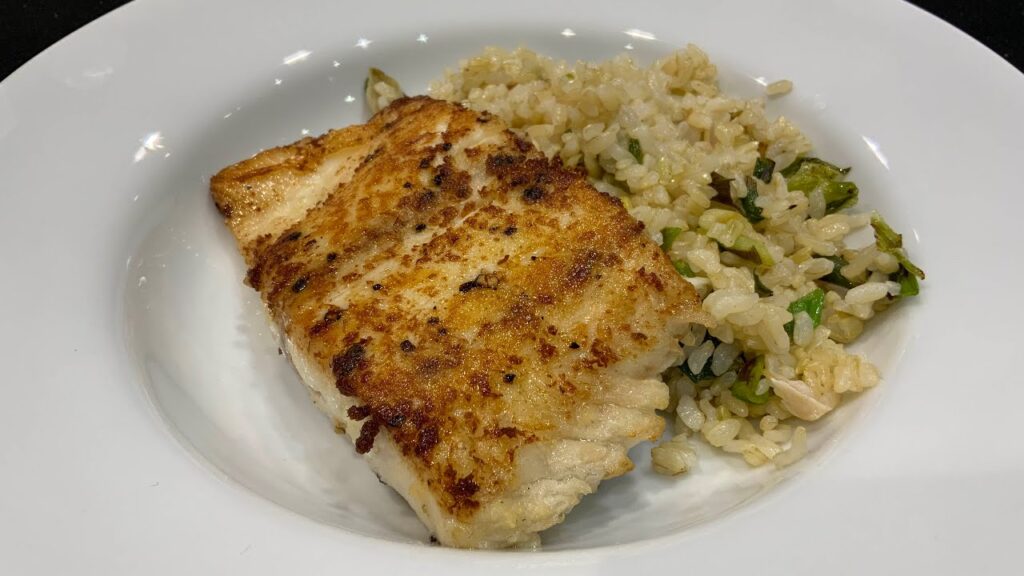 Ginger-crusted bass over vinegar rice displayed on a white dish.